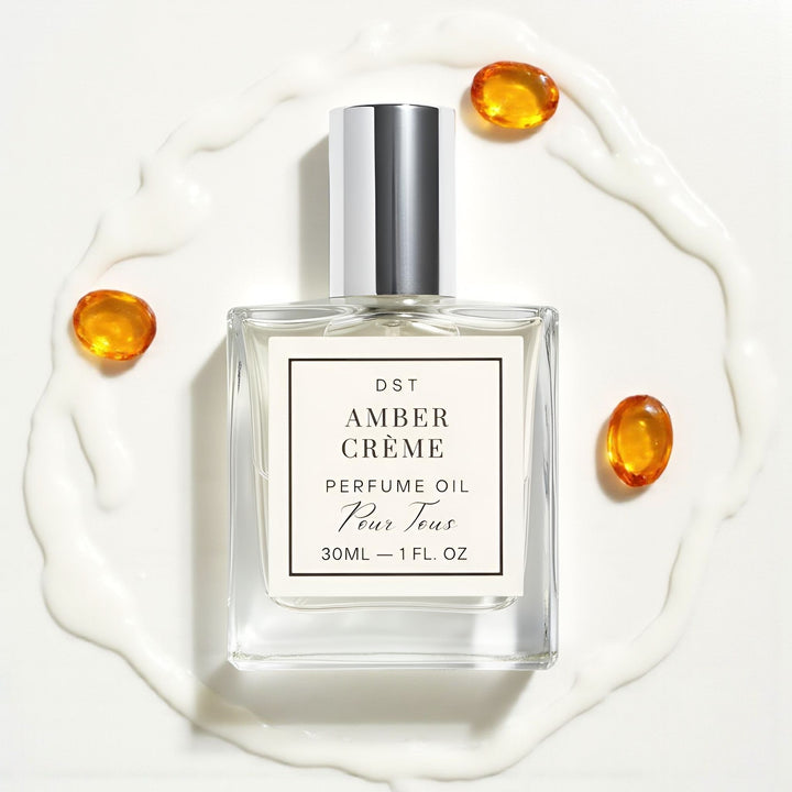 Perfume oil bottle labeled 'Amber Cèreme' on a white background with amber droplets.