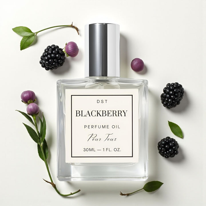 Perfume oil bottle labeled 'Blackberry' surrounded by blackberries on a light background