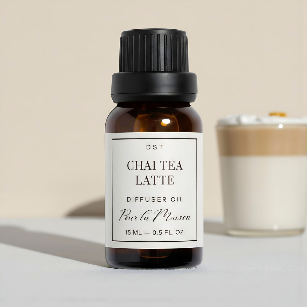 Bottle of Chai Tea Latte diffuser oil with a candle in the background on a neutral surface