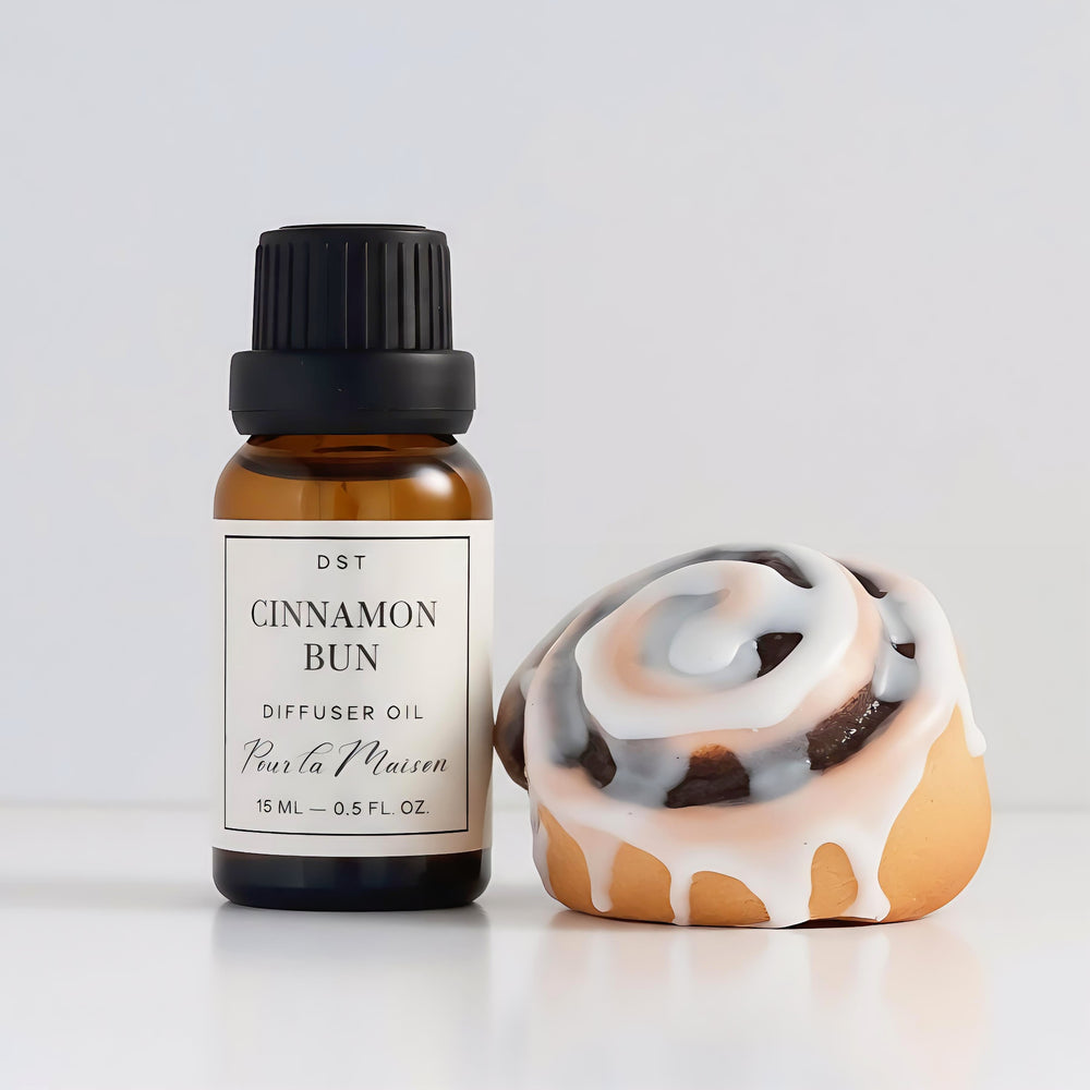 Cinnamon Bun diffuser oil bottle and packaging on a wooden tray with a light background