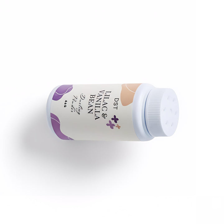 DST Fragrances Lilac Vanilla Bean Powder Scented Bottle laying on its side showing dispenser holes in cap on a white background.