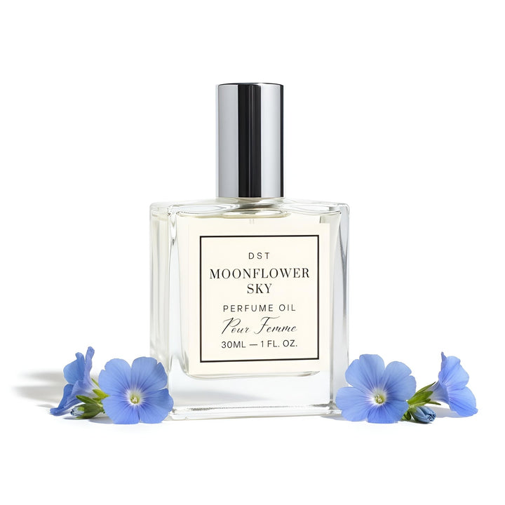 Perfume oil bottle labeled 'Moonflower Sky' surrounded by blue flowers on a white background