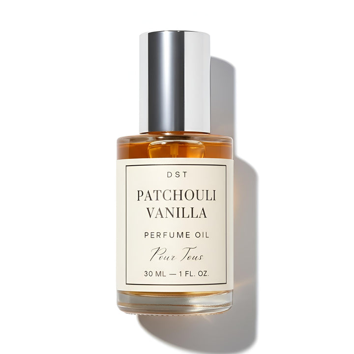 Bottle of Patchouli Vanilla perfume oil by DST Fragrances on a reflective surface with vanilla beans.