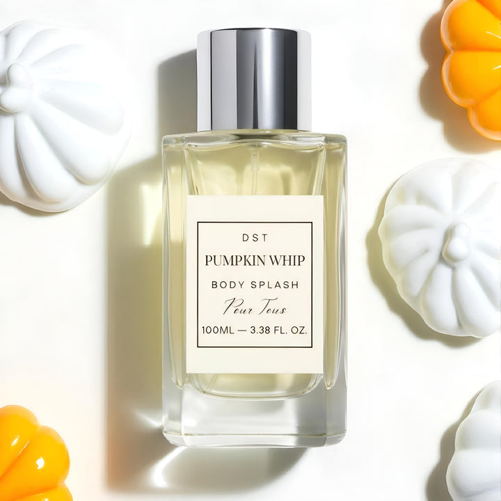 Bottle of 'Pumpkin Whip' body splash with decorative pumpkins and whipped cream on a light background