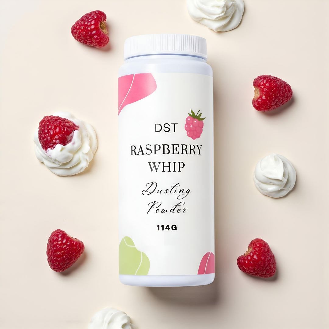 Bottle of Raspberry Whip Body Powder against a pink background with green leaves and raspberries.