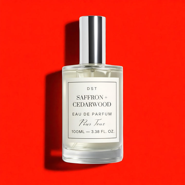 Perfume bottle labeled 'Saffron + Cedarwood' on a red background