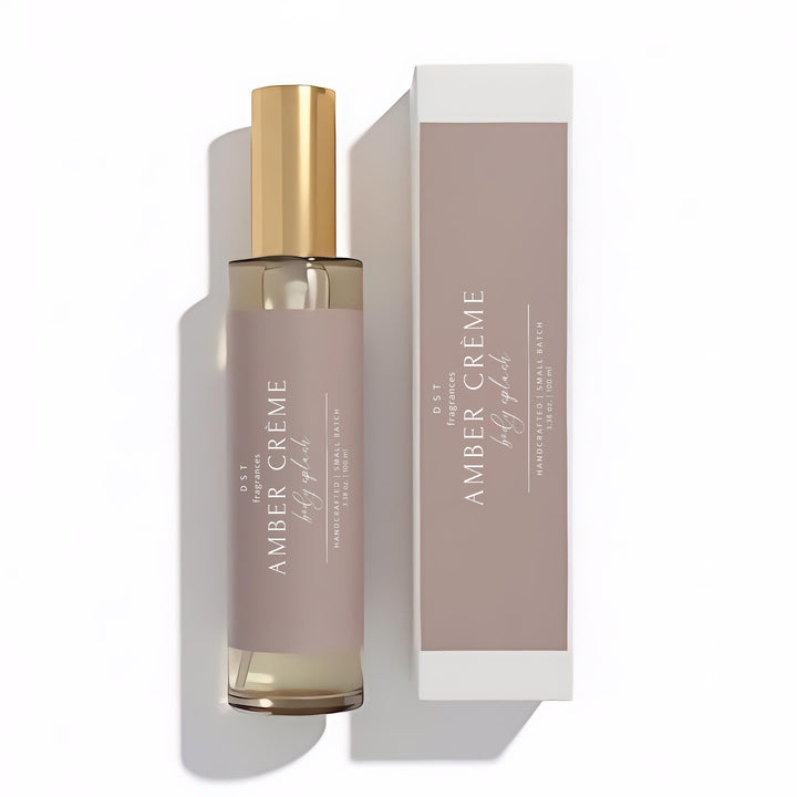 100ml bottle of Amber Crème scented Body Splash and its box by DST Fragrances against a white background.