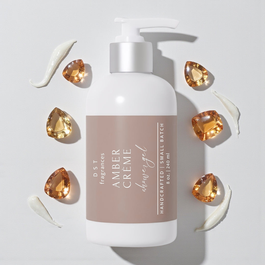 240ml bottle of Amber Crème scented Shower Gel by DST Fragrances against a white background with amber gemstones and spilled cream.