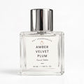 A 50 ml clear glass perfume bottle with a reflective silver cap, labeled 'AMBER VELVET PLUM' by DST FRAGRANCES, on a clean white background.