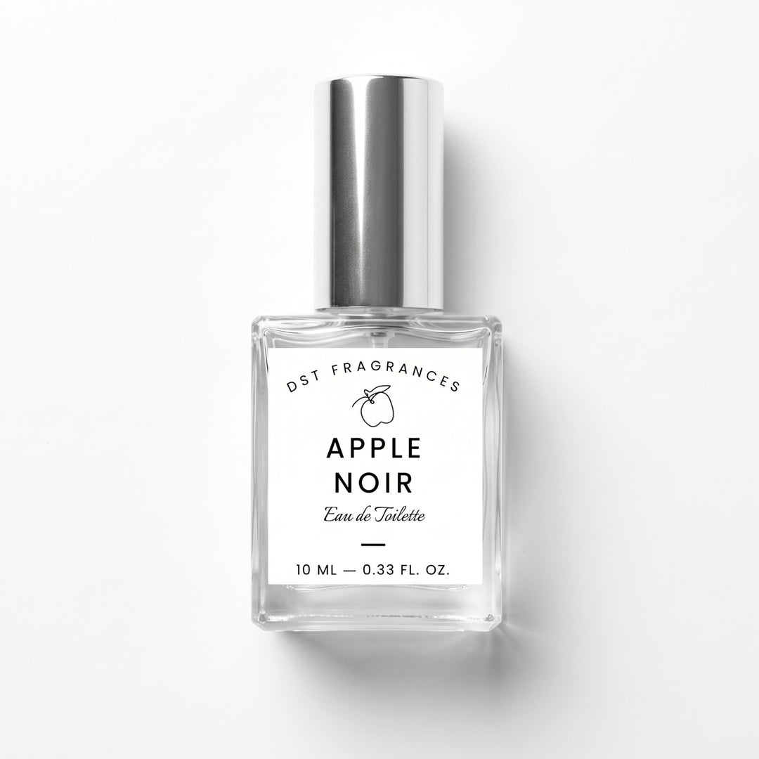 A 10 ml clear glass bottle of DST Fragrances Apple Noir Eau de Toilette with a reflective silver cap and a white label, set against a plain white background with a soft shadow.