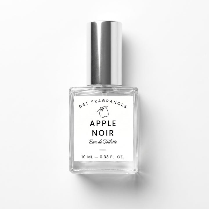 A 10 ml clear glass bottle of DST Fragrances Apple Noir Eau de Toilette with a reflective silver cap and a white label, set against a plain white background with a soft shadow.