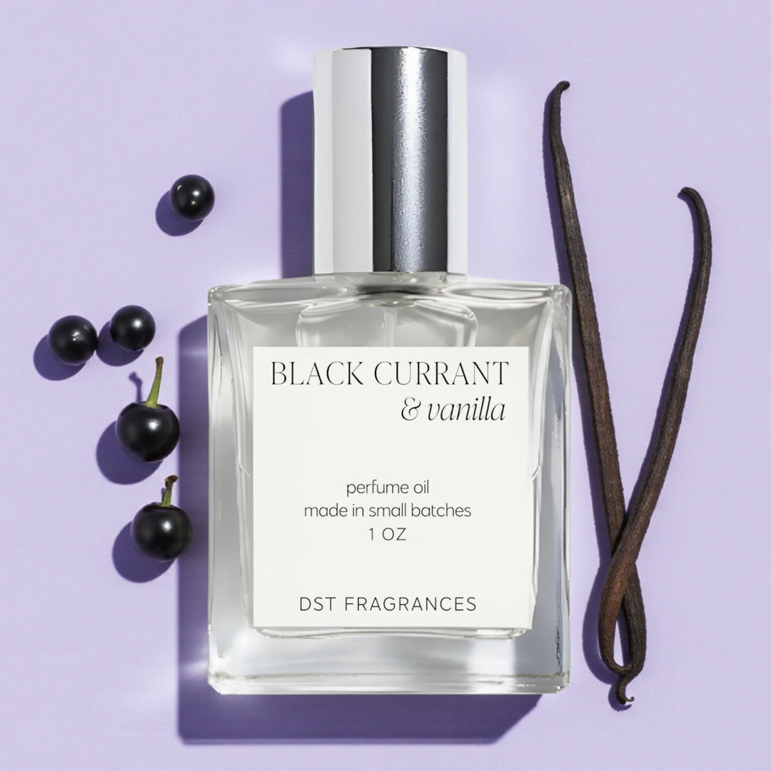 Perfume oil bottle labeled 'Black Currant & Vanilla' with black currants and a vanilla bean on a purple background