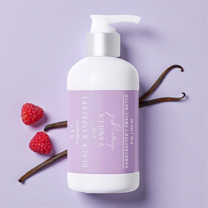 240ml bottle of Black Raspberry Vanilla Scented Shower Gel laying on a pastel purple surface with vanilla beans and raspberries.