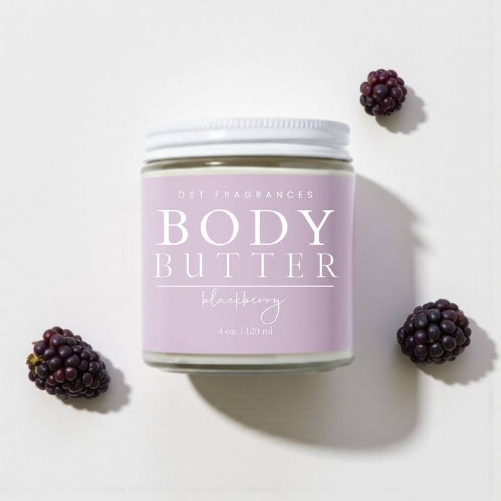4oz jar of Blackberry scented Body Butter by DST Fragrances against a white background with blackberries surrounding the jar.
