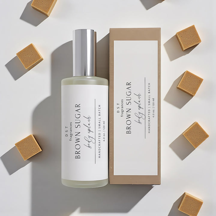 4oz bottle of Brown Sugar Body splash and its box by dst fragrances laying on a beige surface with cubes of brown sugar.