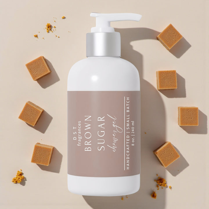 240ml bottle of Brown Sugar Scented Shower Gel and its box against a tan background with cubes of brown sugar scattered around the bottle.