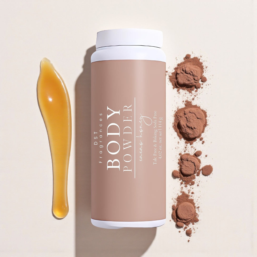 114g bottle of Cacao Honey Body Powder by DST Fragrances laying on a cream-colored surface with spilled honey and small mounds of cocoa powder.