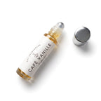 A small glass rollerball perfume oil bottle labeled 'CAFÉ VANILLE' by DST Fragrances, shown on a white background with its silver cap removed and placed beside it.