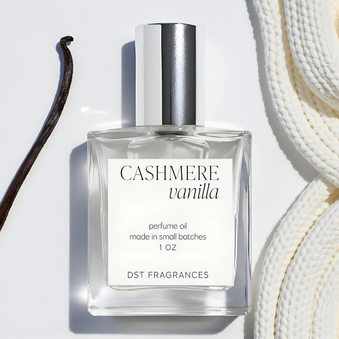 30ml bottle Cashmere Vanilla Perfume Oil by DST Fragrances on a ivory backdrop with vanilla bean and cashmere scarf in the background.