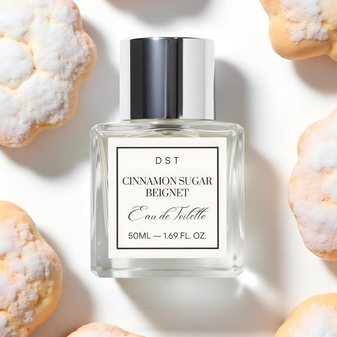 Perfume bottle labeled 'Cinnamon Sugar Beignet' by DST on a light background with pastries.