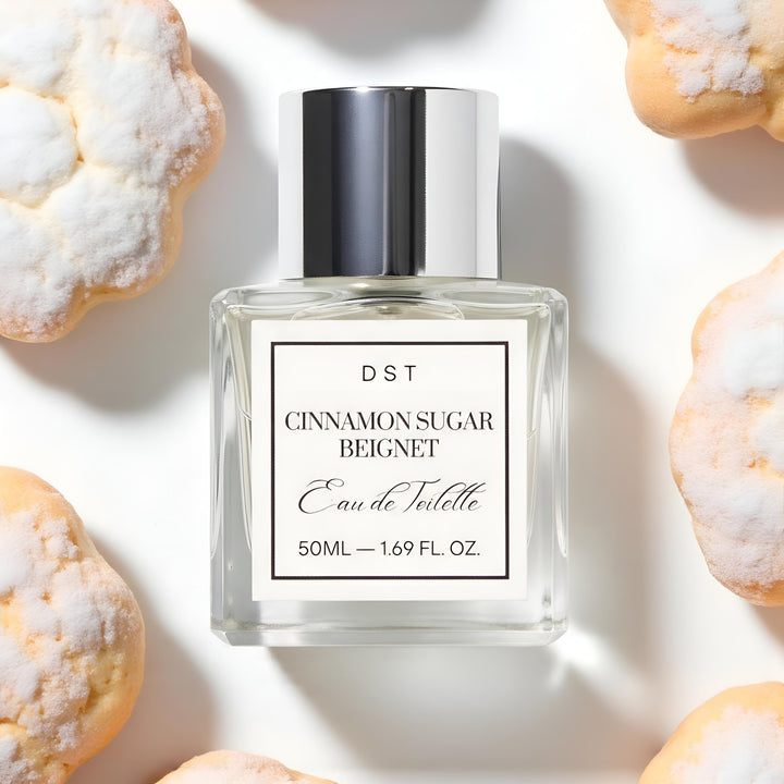 Perfume bottle labeled 'Cinnamon Sugar Beignet' by DST on a light background with pastries.