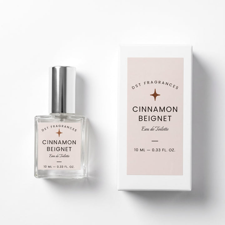 10ml Bottle of Cinnamon Beignet Eau de Toilette spray and its box by DST Fragrances against a white background.