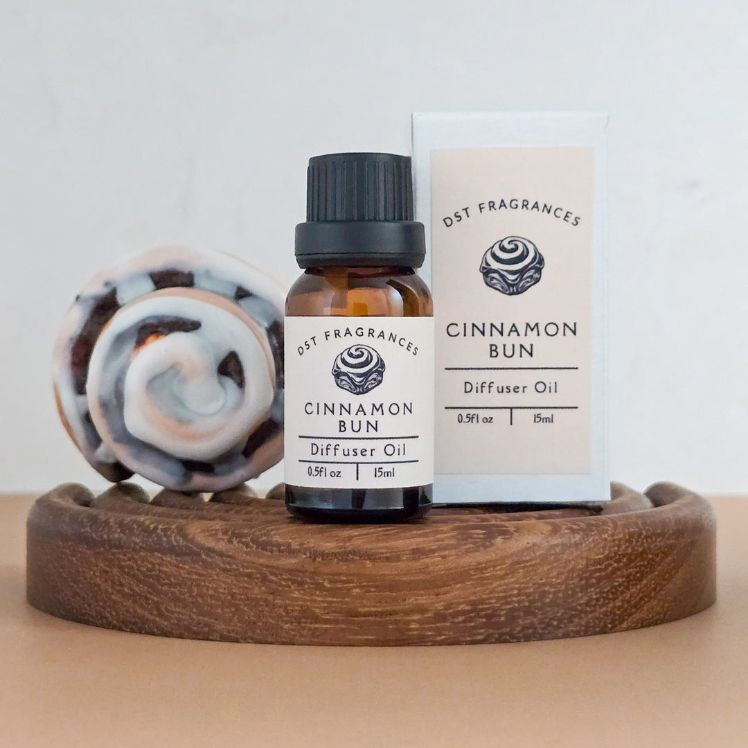 Cinnamon Bun diffuser oil bottle and packaging on a wooden tray with a light background