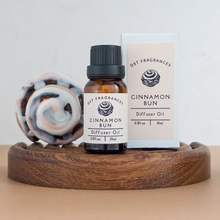 Cinnamon Bun diffuser oil bottle and packaging on a wooden tray with a light background