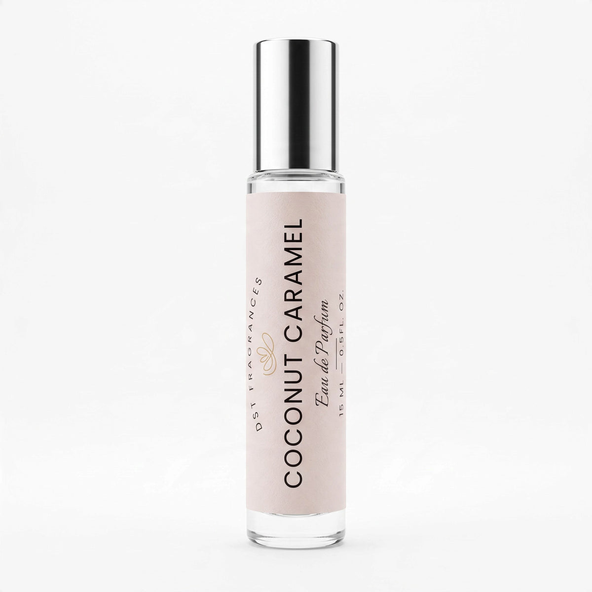 A clear glass rollerball perfume bottle with a metallic silver cap and a pale blush pink label reading 'COCONUT CARAMEL' and 'Eau de Parfum'.