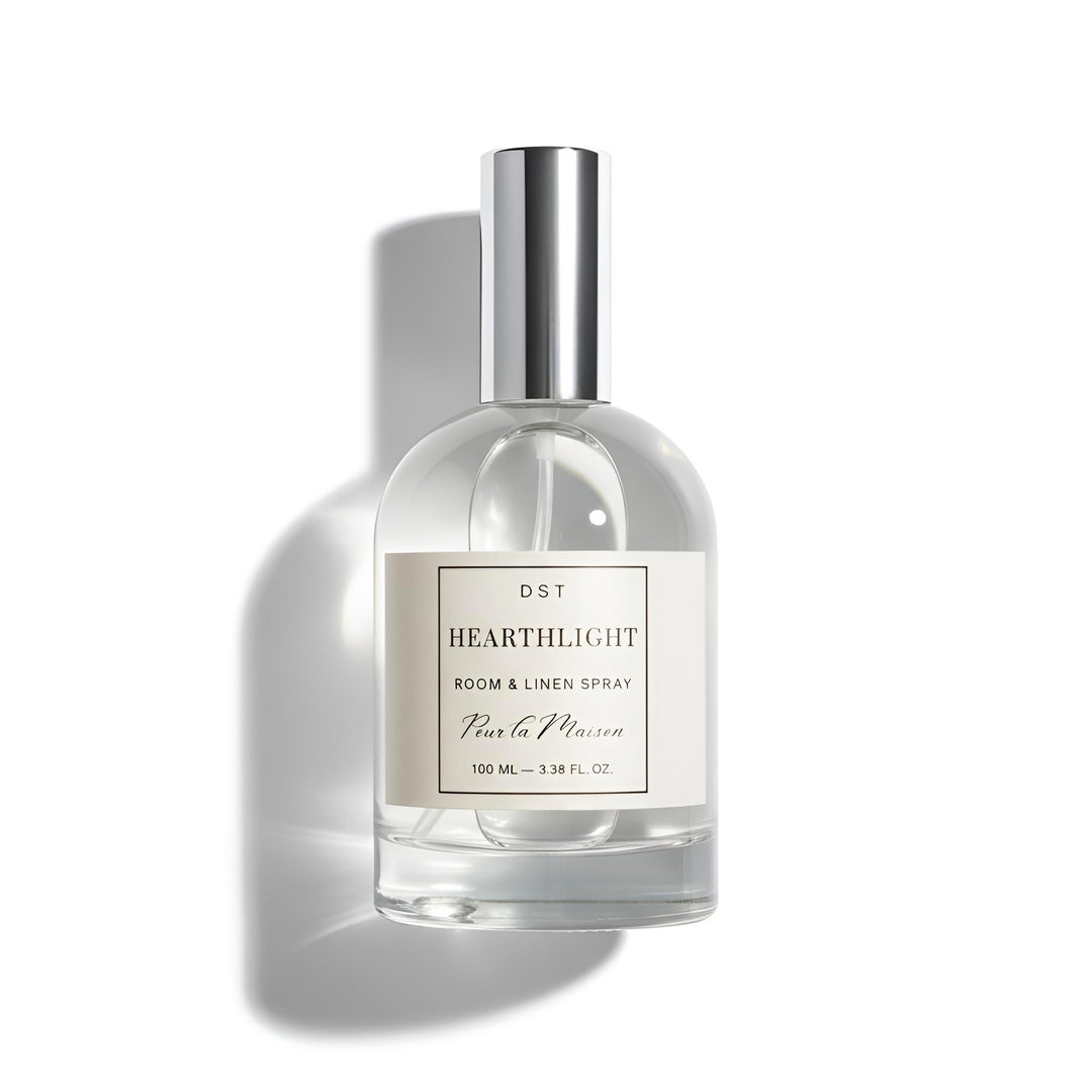 Clear bottle of 'Hearthlight' room & linen spray with a silver cap on a white background