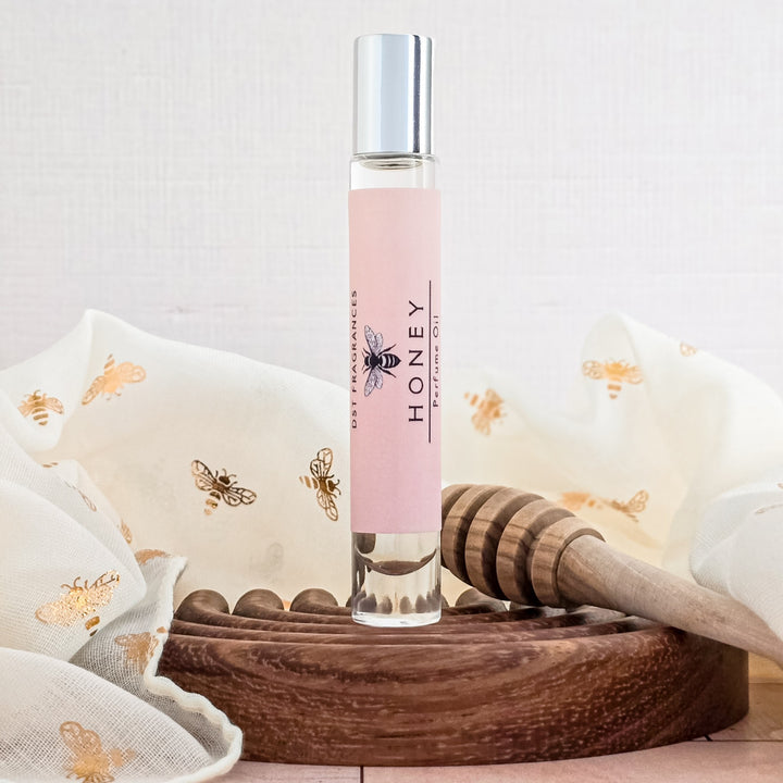 Roll-on bottle labeled 'Honey' with a wooden honey dipper on a textured surface.