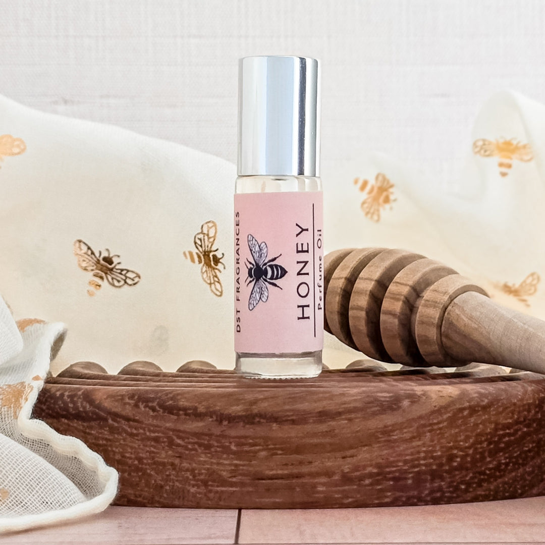 Roll-on bottle labeled 'Honey' with a bee design on a wooden tray.