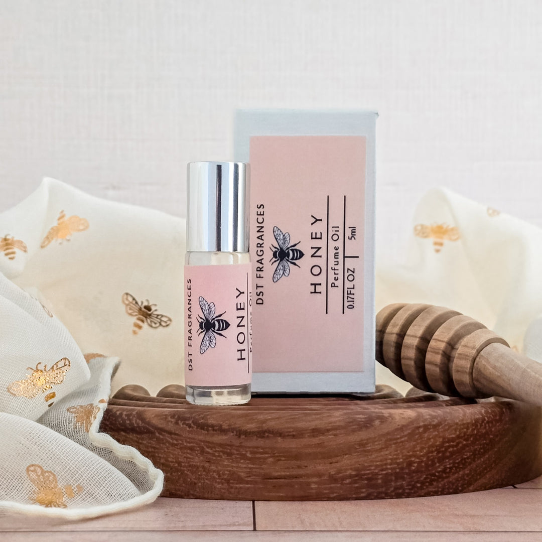 Honey perfume bottle and packaging on a wooden surface with decorative elements.