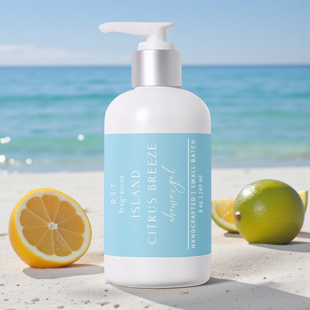 240ml bottle of Island Citrus Breeze scented Shower gel by DST Fragrances sitting on a sandy beach with Lemons and Limes and the ocean in the background.