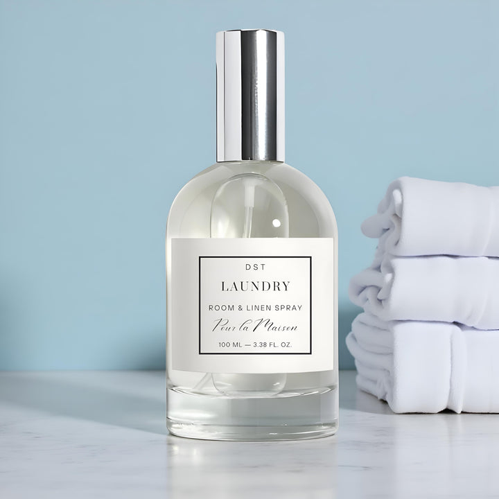 Laundry room and linen spray bottle with folded white towels on a light blue background