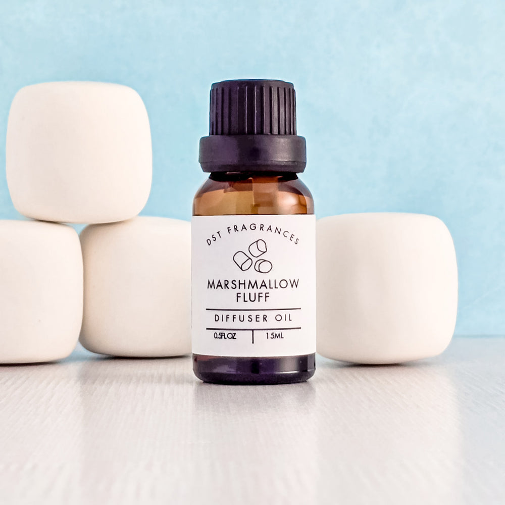 Bottle of Marshmallow Fluff diffuser oil with marshmallows on a light blue background