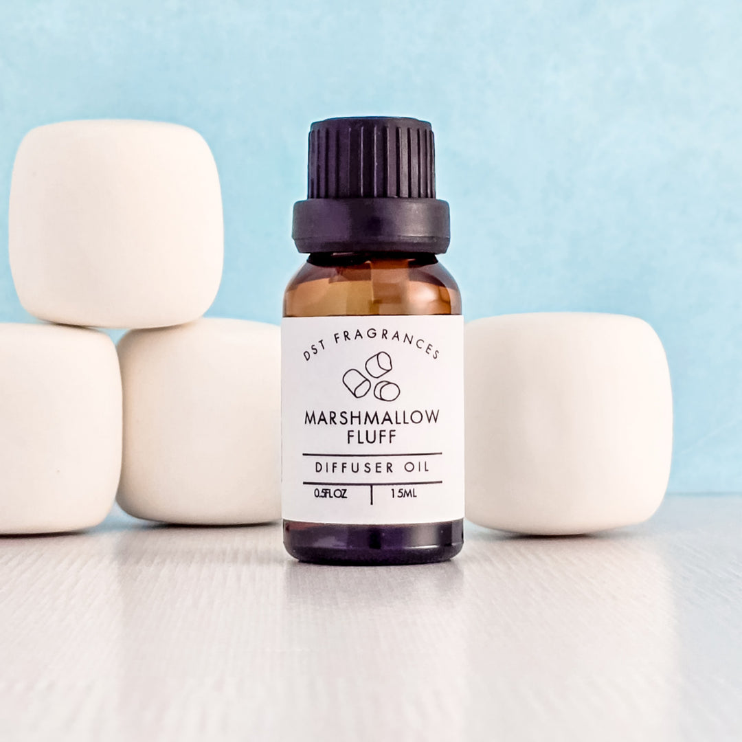 Bottle of Marshmallow Fluff diffuser oil with marshmallows on a light blue background
