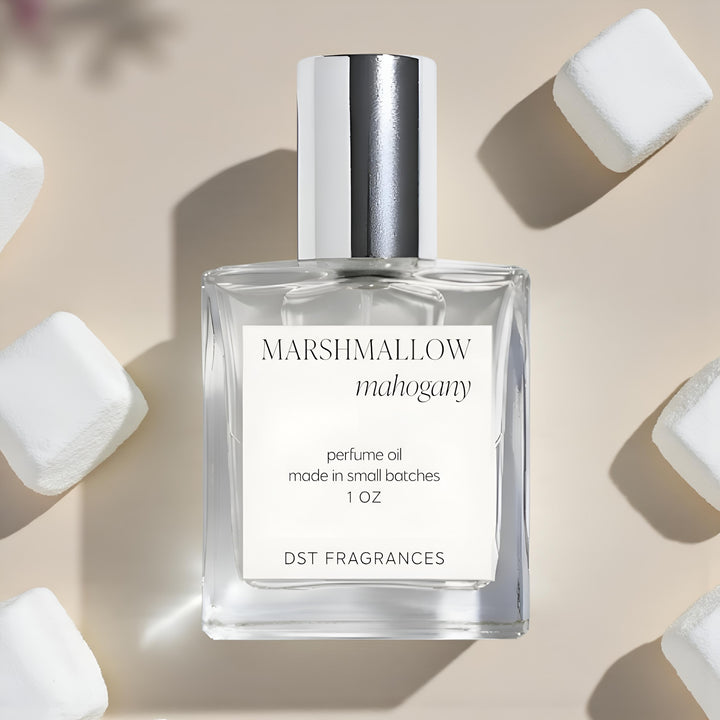 Perfume oil bottle labeled 'Marshmallow Mahogany' surrounded by marshmallows on a beige background