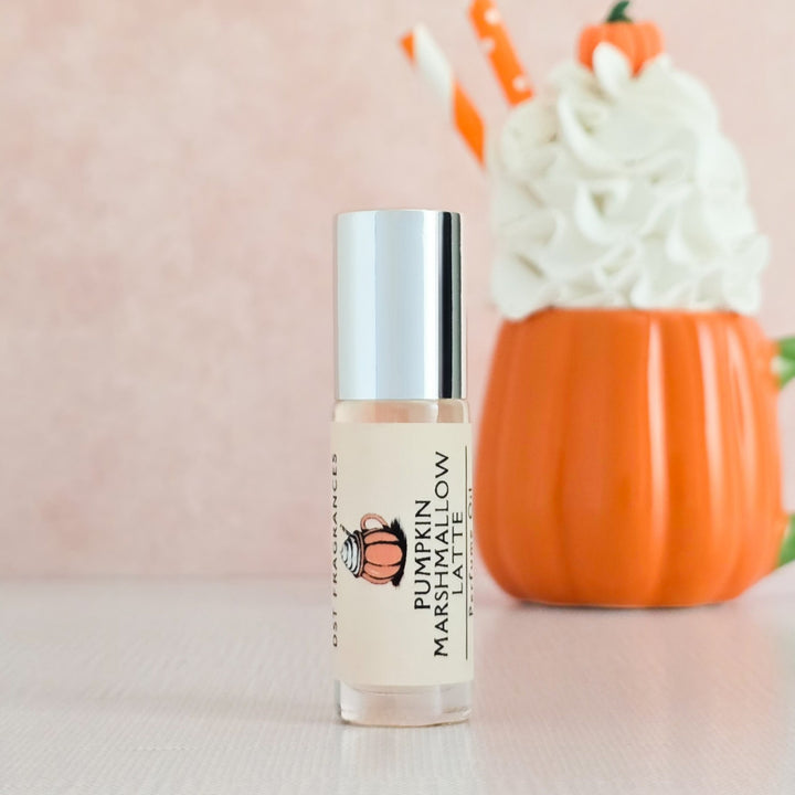 Roll-on bottle labeled 'Pumpkin Marshmallow Latte' with a pumpkin-themed cup in the background.