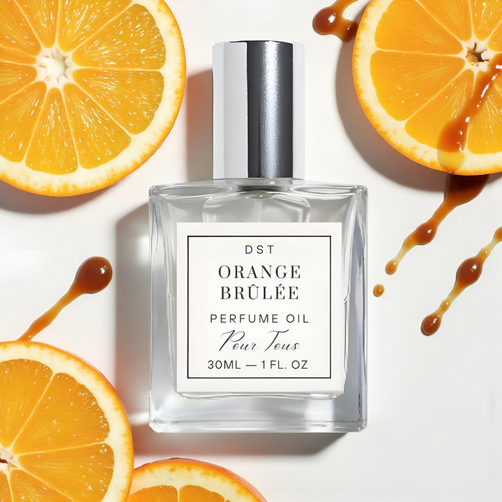 Perfume oil bottle labeled 'Orange Brèlé' with orange slices and syrup on a white background