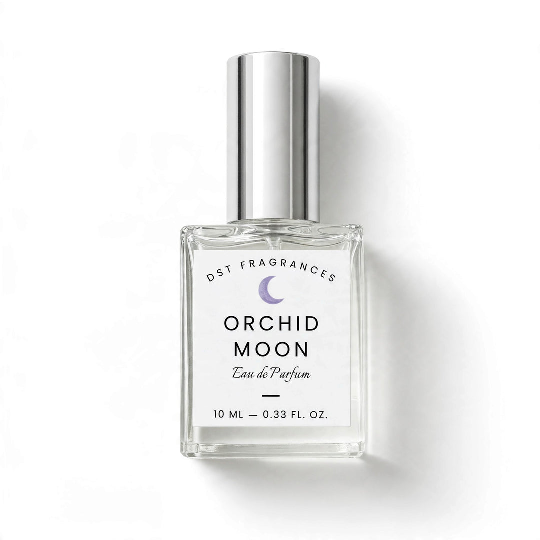 A 10 ml clear glass perfume bottle with a silver cap, featuring a white label with black text and a purple crescent moon logo. The label reads DST FRAGRANCES ORCHID MOON Eau de Parfum&