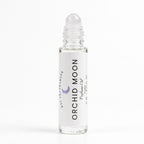 A clear glass rollerball bottle of DST Fragrances Orchid Moon Perfume Oil with a white label and a clear cap, set against a plain white background.