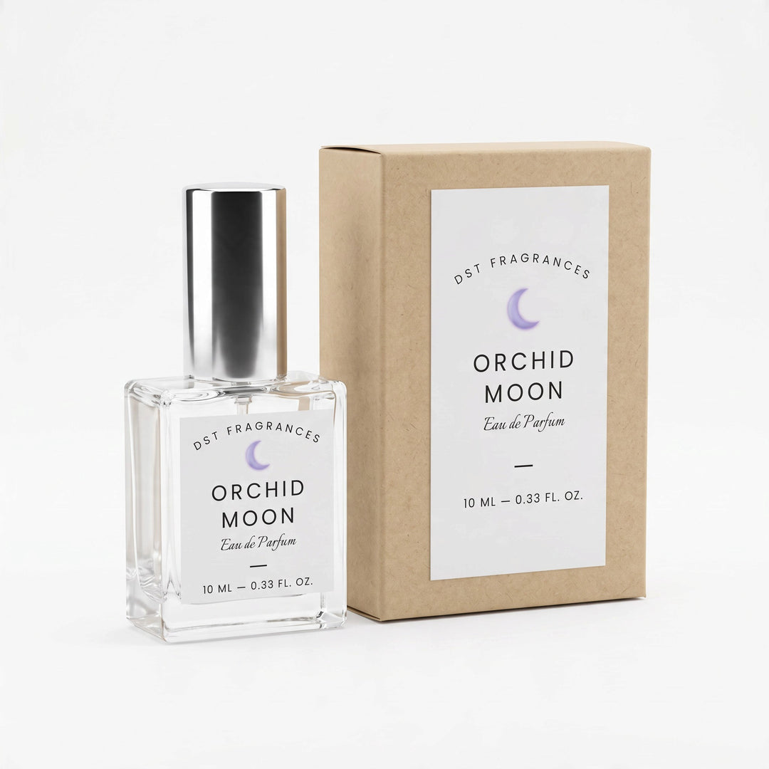 A 10 mL clear glass perfume bottle with a silver cap stands next to its kraft paper box. Both the bottle and box feature a white label with the brand name &