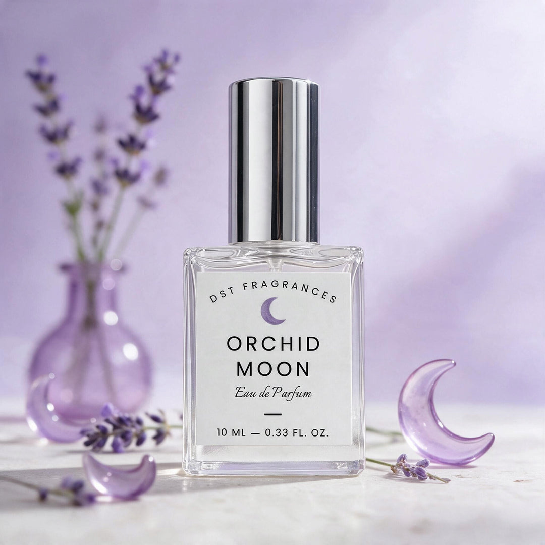 A 10 ml bottle of DST Fragrances Orchid Moon Eau de Parfum, featuring a clear glass bottle and a shiny silver cap, styled with lavender sprigs and purple crescent moon props on a light marble surface against a soft lavender background.