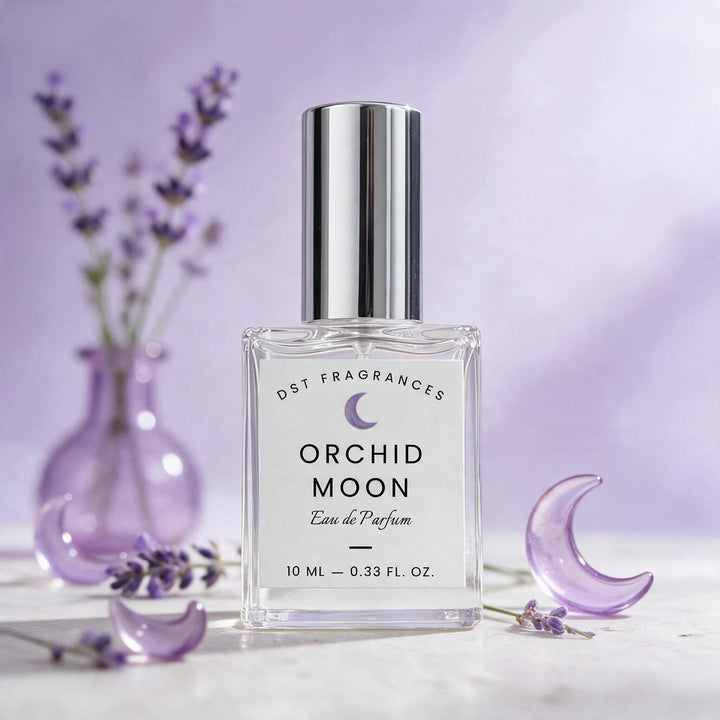 A 10 ml bottle of DST Fragrances Orchid Moon Eau de Parfum, featuring a clear glass bottle and a shiny silver cap, styled with lavender sprigs and purple crescent moon props on a light marble surface against a soft lavender background.