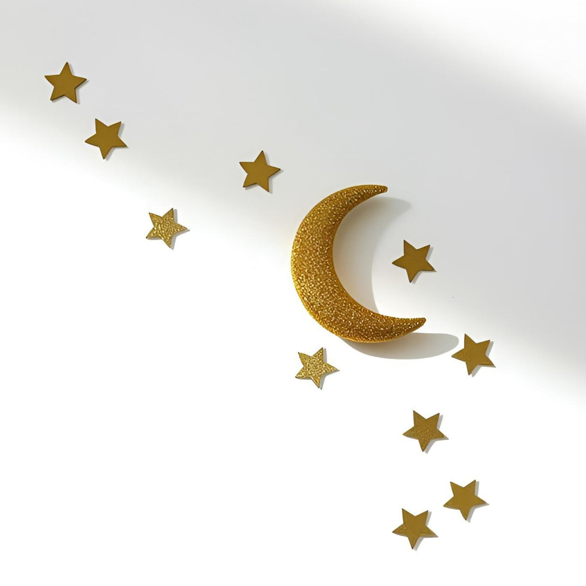 Gold crescent moon and star wall decor arranged diagonally on a white background with soft shadows.
