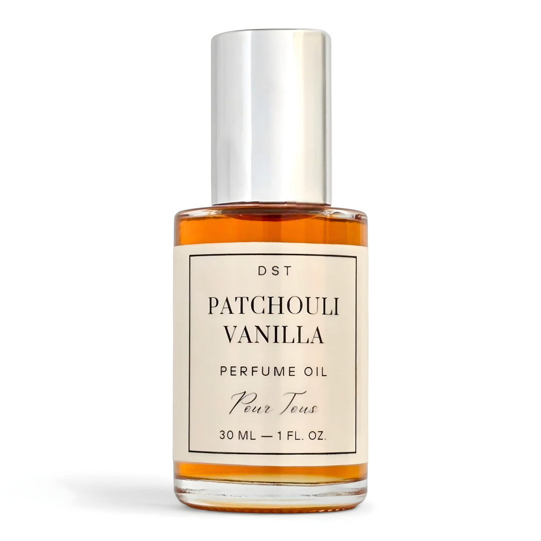 Bottle of Patchouli Vanilla perfume oil by DST Fragrances on a reflective surface with vanilla beans.
