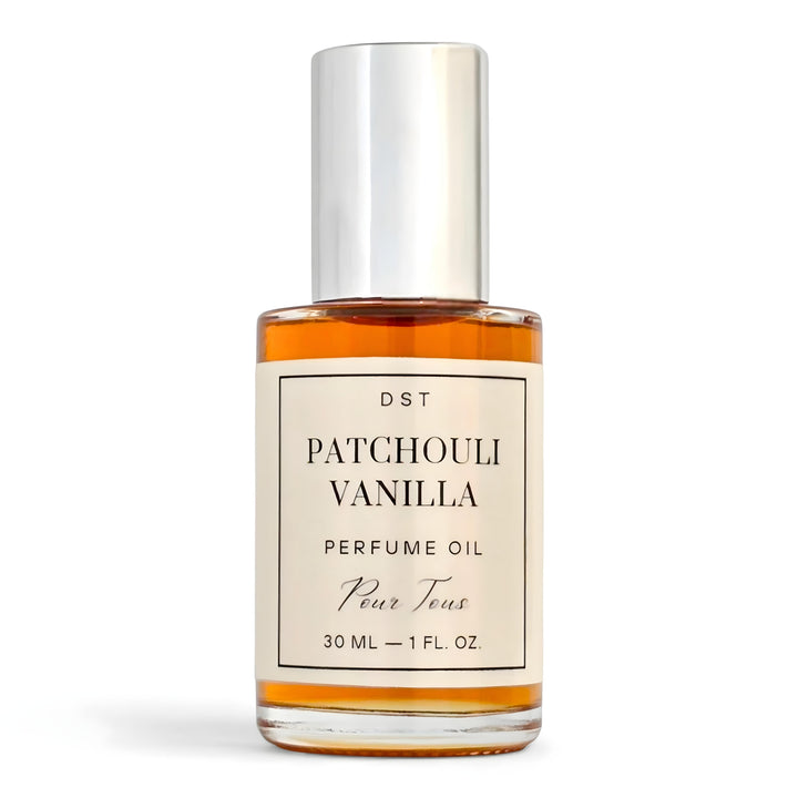 Bottle of Patchouli Vanilla perfume oil by DST Fragrances on a reflective surface with vanilla beans.