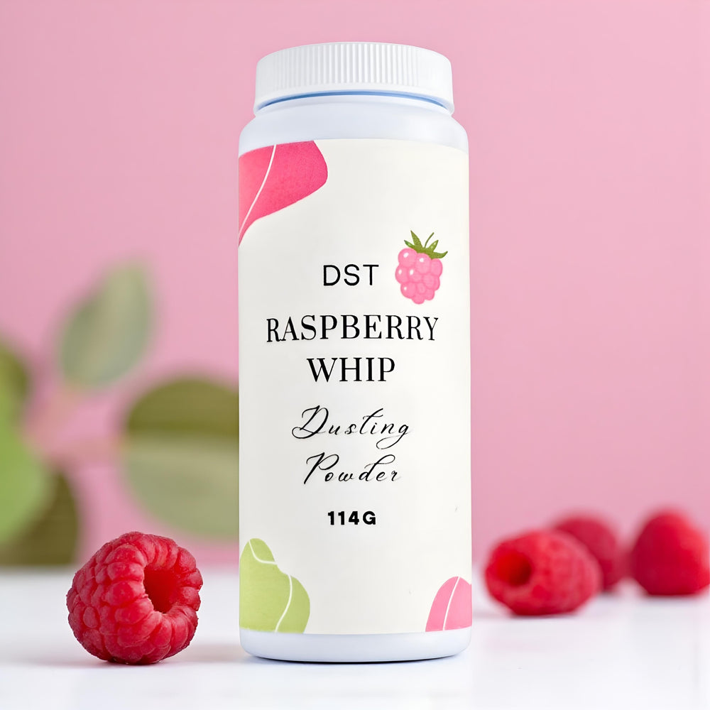 Bottle of Raspberry Whip Body Powder against a pink background with green leaves and raspberries. 