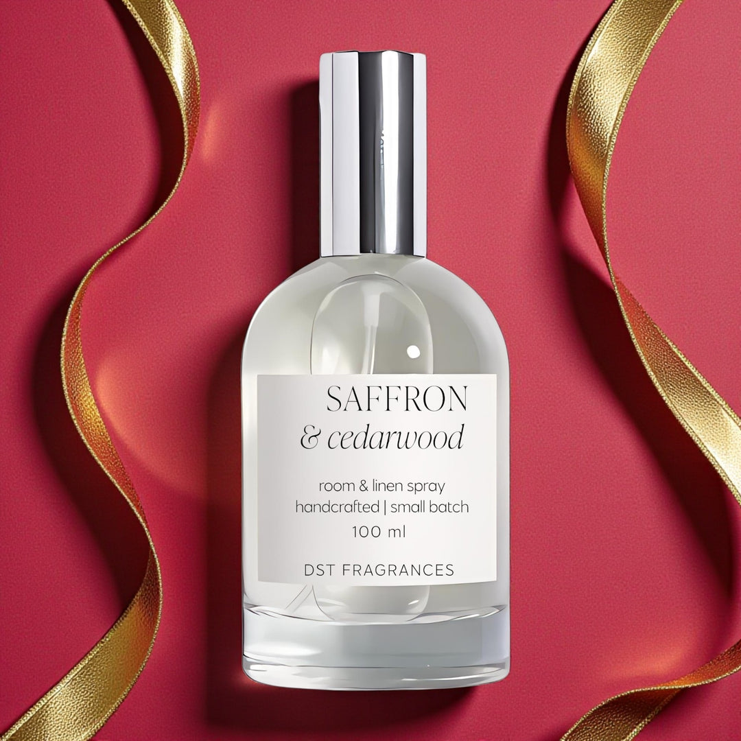 100ml bottle of Saffron Cedarwood Room Linen by DST Fragrances against a red background with gold bokeh lights.